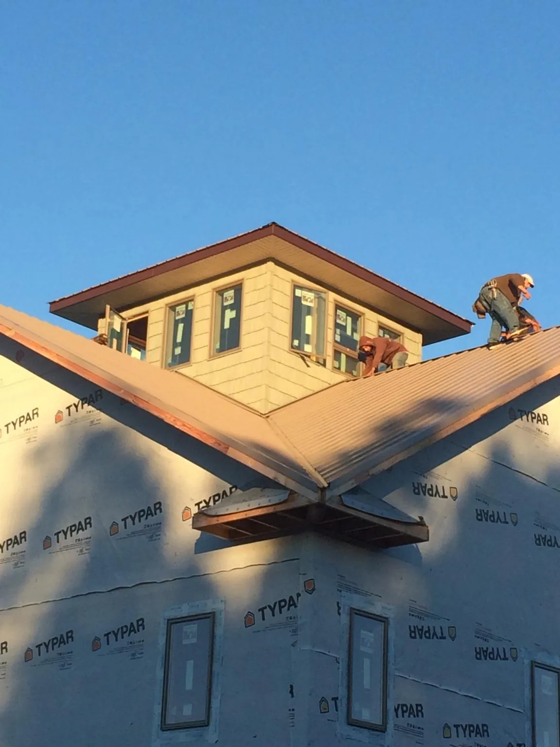 Roofers working around a rooftop cupola on a new metal roof at sunset — Roof Waterproofing in Cunningham by Roofing Brothers